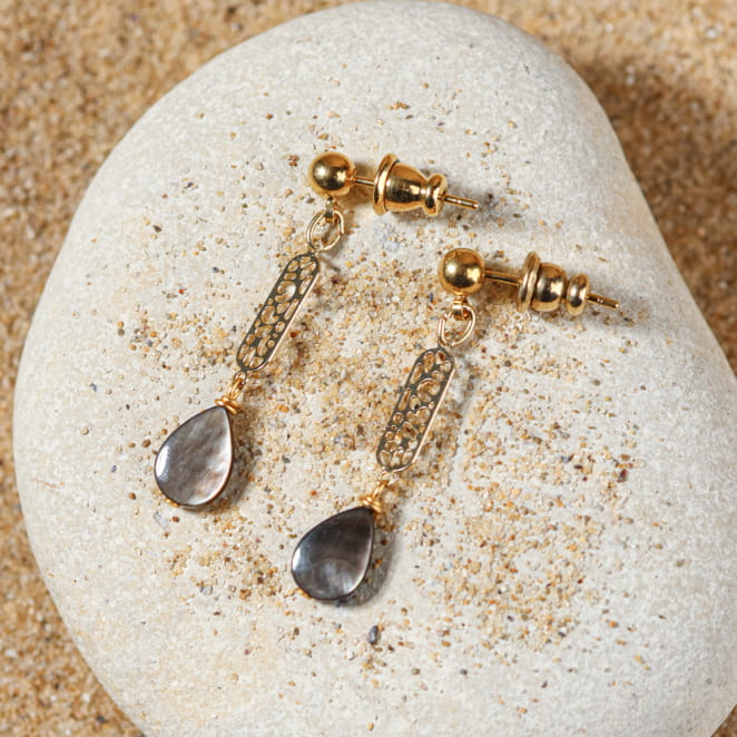 Boucles d’oreilles Turini posées en croix sur le sable – fabrication artisanale française