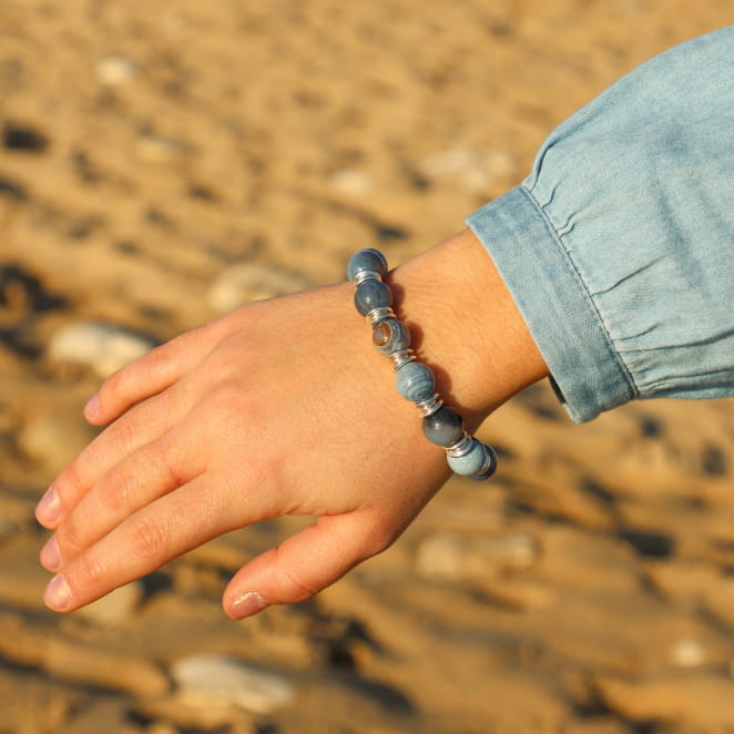 Détail du bracelet Minke bleu et argenté sur fond sable – fabrication artisanale française
