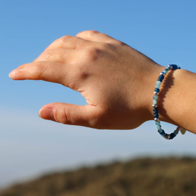 Bracelet bleu ciel et argenté porté sur fond de ciel bleu – création artisanale française