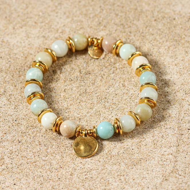 Bracelet Valentina doré et vert d’eau en perles naturelles, posé sur le sable – création artisanale