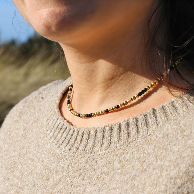 Collier Luciole noir et doré porté au cou, bijou artisanal fabriqué en France