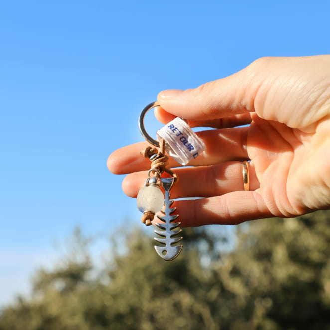 Porte-clés multicolore avec anneau argenté et perles bleues, accroché à une main – création artisanale française