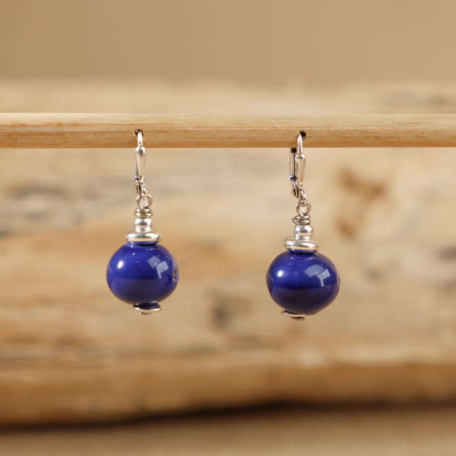 boucles Seiche bleu dur posées à plat, monture en métal argenté et finition brillante