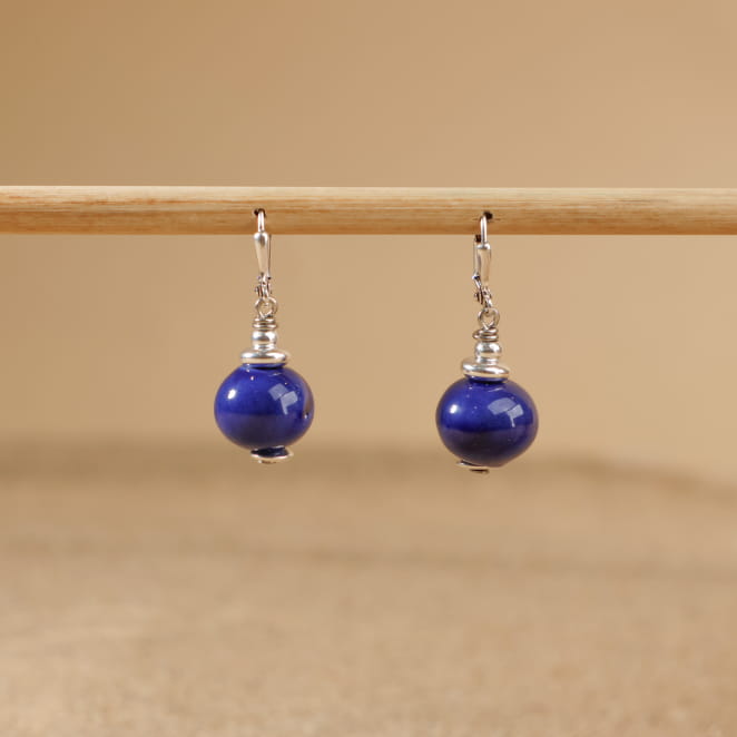 boucles Seiche bleu dur à plat sur fond beige, perles rondes et monture argentée