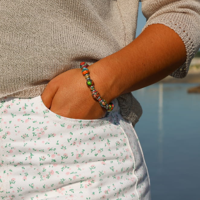 bracelet Jungle argenté à perles multicolores porté avec robe claire