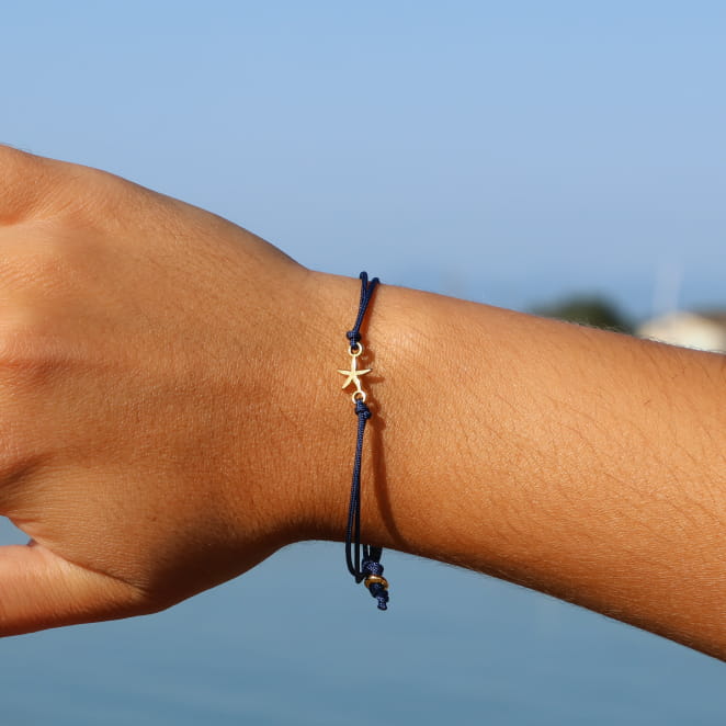 bracelet Transat doré avec cordon bleu marine porté au poignet