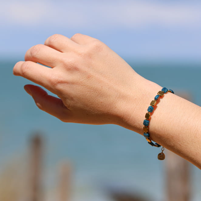 Bracelet artisanal en métal doré avec cordon bleu pétrole, élégance et style marin. Fabriqué en France.