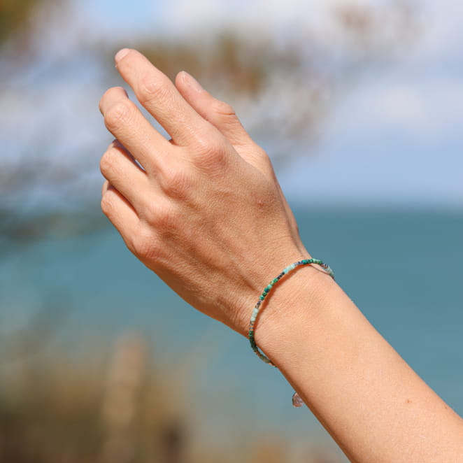 Bracelet artisanal en métal argenté avec cordon vert d’eau, inspiré de l’océan. Création française.