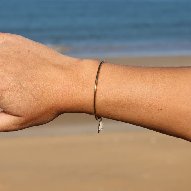 Bracelet jonc porté – bijou en métal doré avec perle émaillée, pompon beige en coton et perles en verre, fabrication artisanale française