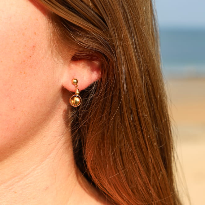 Boucles d’oreilles Astrod en métal doré avec pendentif artisanal, création française.