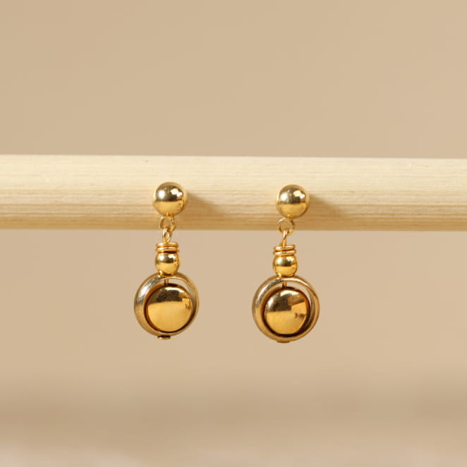 Boucles d’oreilles Astrod en métal doré avec pendentif artisanal, création française.
