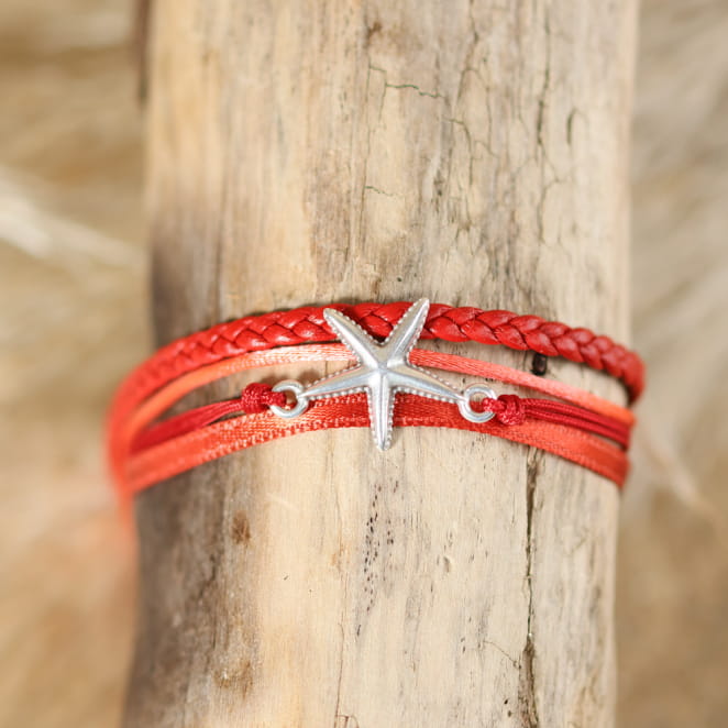 Bracelet Asteroïda Retour de Plage en ruban de satin orange, tresse en cuir rouge, cordon en nylon rouge et cordon en polyester rose, orné d'une étoile de mer en métal plaqué argent 999 et d'une médaille Retour de Plage – bijou artisanal fabriqué en France