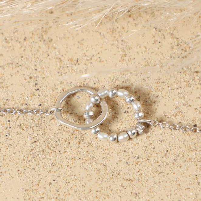 Détail du cercle en métal plaqué argent 999 enlacé dans un anneau de perles de rivière blanches et perles argentées du bracelet Isalie, sur fine chaîne argentée plaqué argent 999.