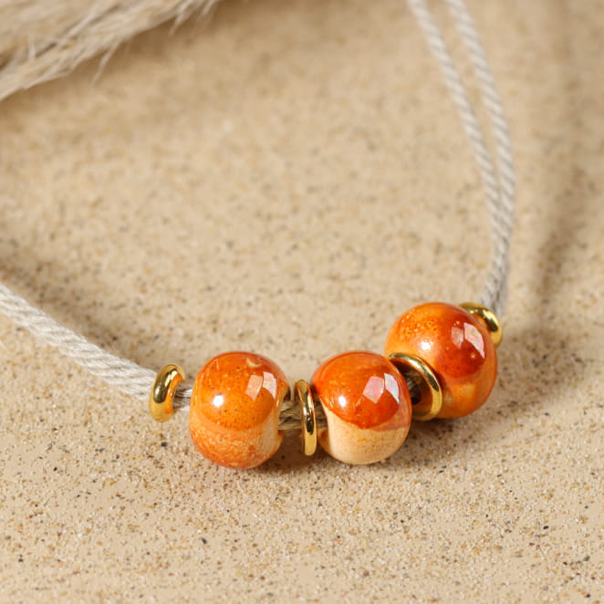 Collier Sepia en métal doré orné de perles orange, bijou artisanal français.