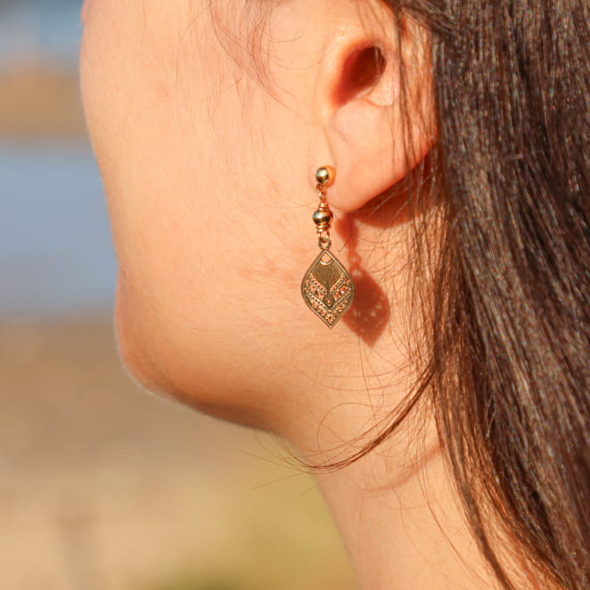 boucles d’oreilles Aïcha dorées avec pendentif rond martelé portées sur oreille percée