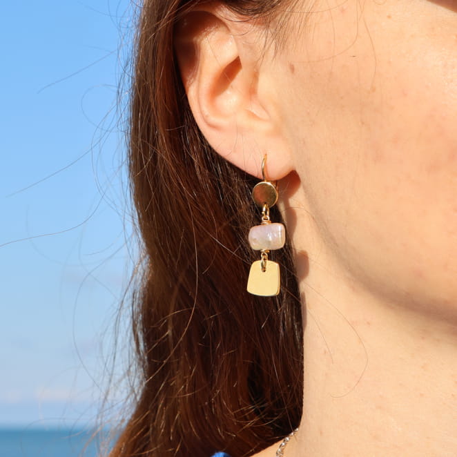 boucles d’oreilles Giens dorées avec pendentif blanc portées