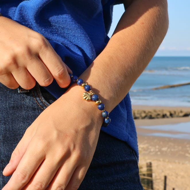 bracelet Konko doré avec perles bleu foncé et fermoir en métal porté au poignet