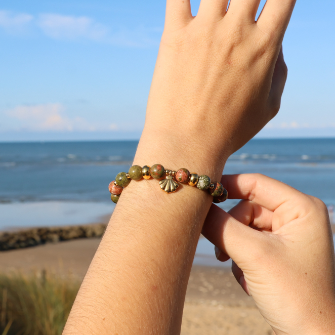 bracelet Konko doré avec perles jaunes et fermoir en métal porté au poignet