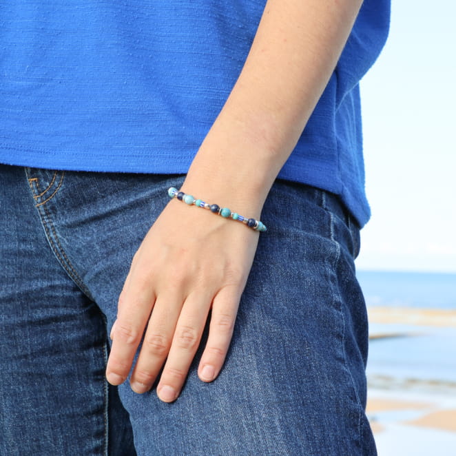 bracelet Konko doré avec perles kaki et fermoir en métal porté au poignet