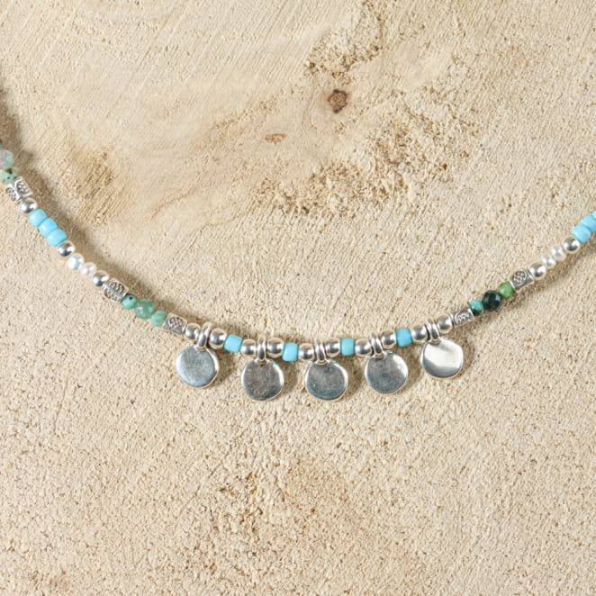 collier Granita argenté avec perles bleu ciel et multicolores sur sable clair