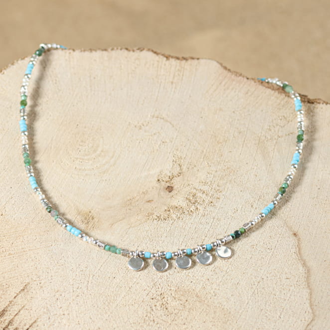 collier Granita argenté avec perles bleu ciel et multicolores sur sable clair