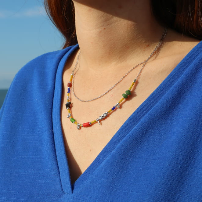 collier Turaco argenté à perles multicolores porté avec tenue bleue