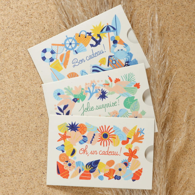 Carte cadeau physique Retour de Plage avec design floral et inscription 'Jolie surprise !', présentée sur un fond naturel