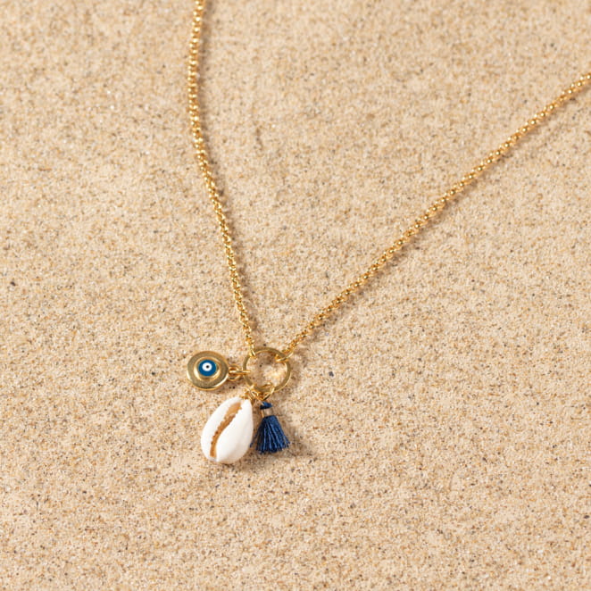 Collier Grèce doré avec coquillage et perle bleu marine, ambiance estivale.