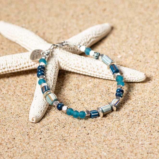 bracelet enfant Match, tressage bleu, gris et multicolore avec perles, sur fond sable