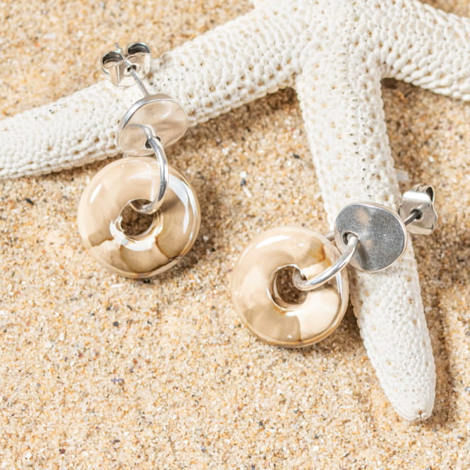 Détail des boucles Donuts posées sur le sable, design épuré et fini brillant