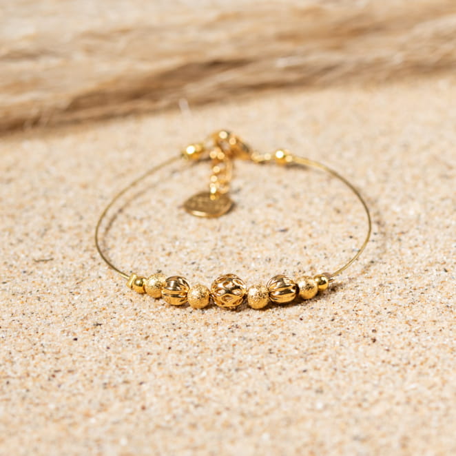 Bracelet Leslie doré mis en scène sur fond neutre, bijou lumineux et intemporel.