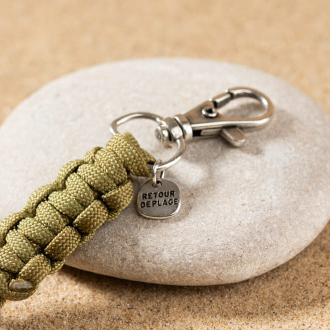 Le porte-clefs Denis est un porte-clefs composé d'un mousqueton en métal plaqué argent 999, d'un noeud en tête d'alouette en polyester kaki et d'un anneau en métal plaqué argent 999.