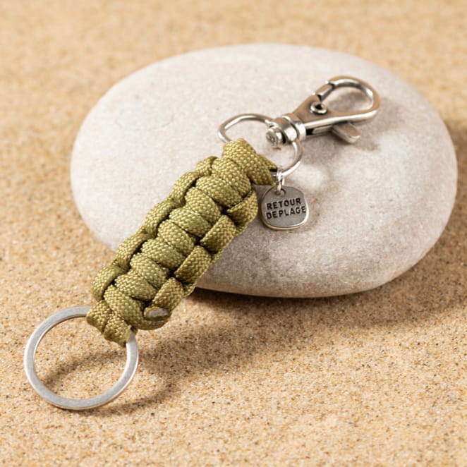 Le porte-clefs Denis est un porte-clefs composé d'un mousqueton en métal plaqué argent 999, d'un noeud en tête d'alouette en polyester kaki et d'un anneau en métal plaqué argent 999.