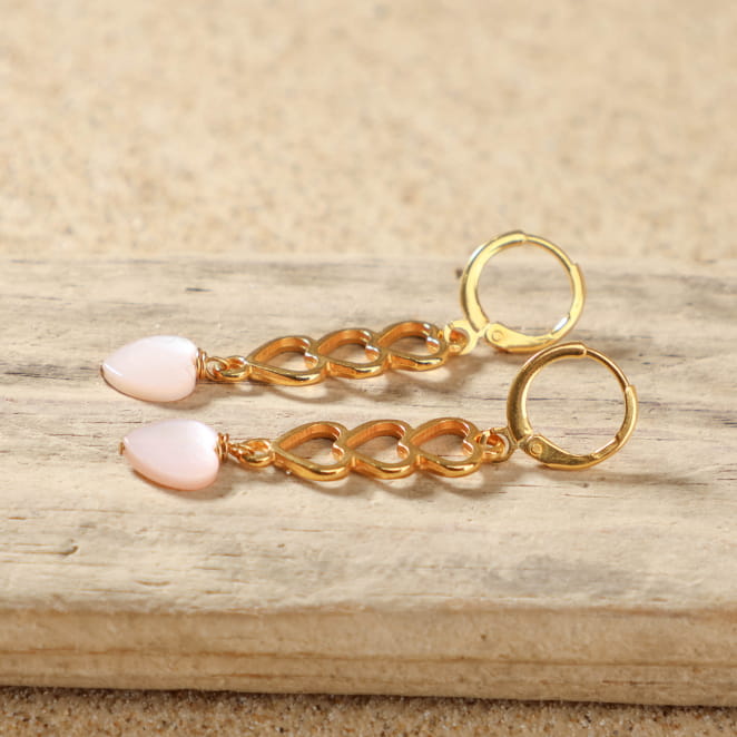 Détail des boucles d'oreilles Aina avec trois cœurs dorés et perle en nacre rose en forme de cœur – création artisanale française élégante