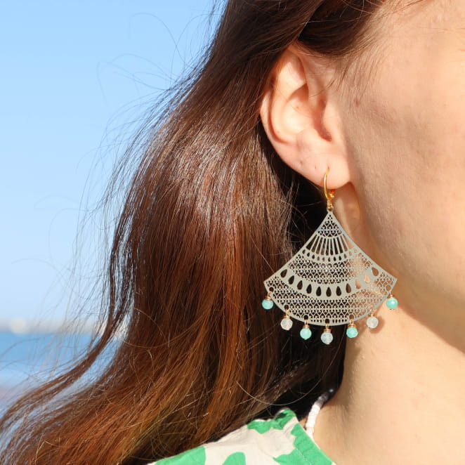 boucles Manel dorées avec perles vert d’eau portées à l’oreille sur cheveux lâchés