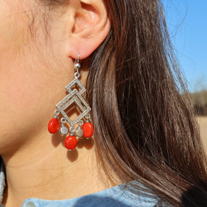 Boucles d’oreilles pendantes argentées avec perles rouges, look solaire et affirmé.
