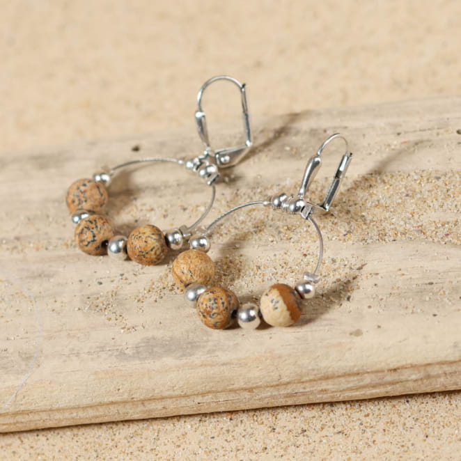 Boucles Sina en métal argenté et perles beige naturelles, pour un look doux et lumineux.