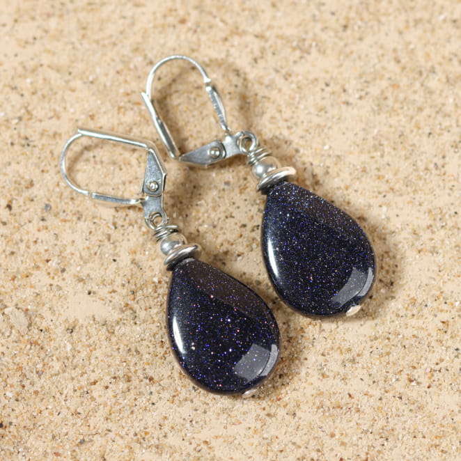 Autre vue des boucles d’oreilles Sol bleu marine sur fond sable – artisanat élégant