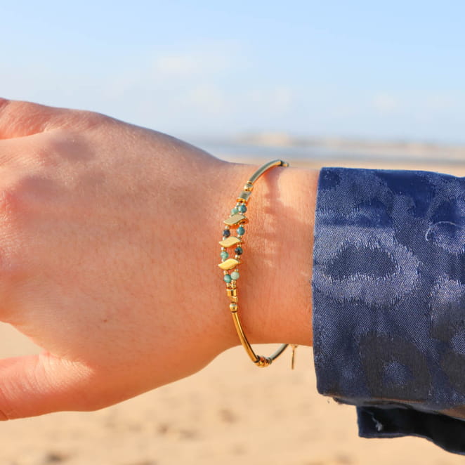 Bracelet Anisha doré avec perles bleu gris, porté en bord de mer – création fait main en France