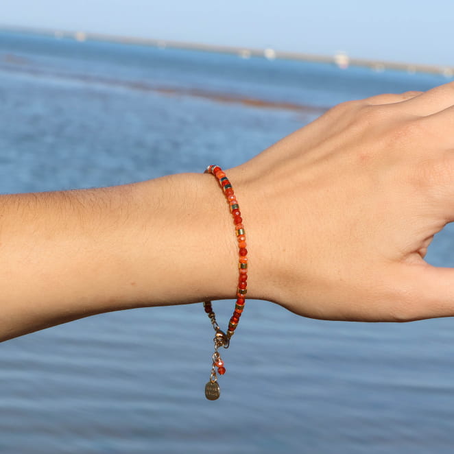 bracelet Clémentine doré et orange porté au poignet en extérieur