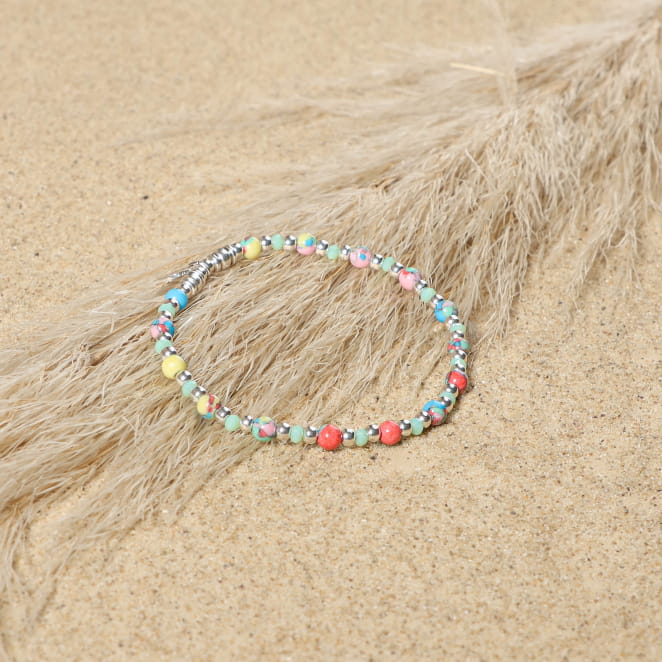 bracelet Doux argenté à perles multicolores enroulé sur sable clair