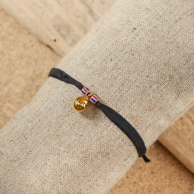 bracelet Friendly doré avec cordon noir sur support sable clair