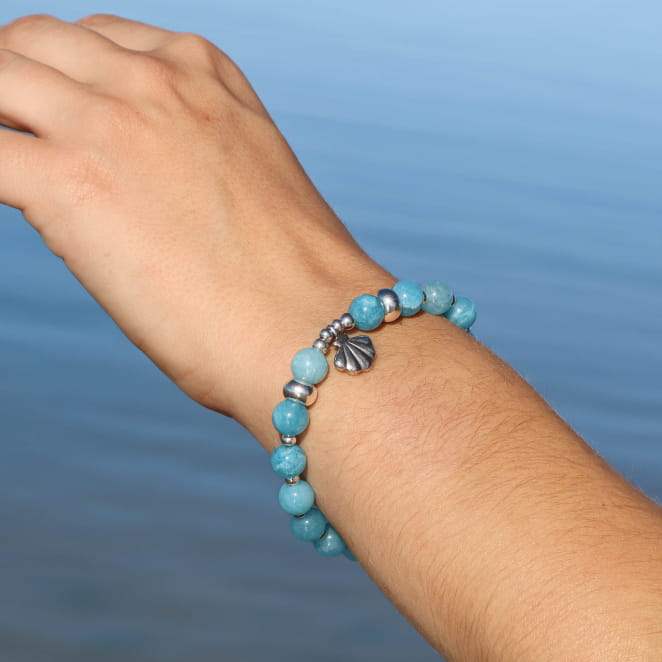 bracelet Konko argenté avec perles bleu ciel porté au poignet en bord de mer