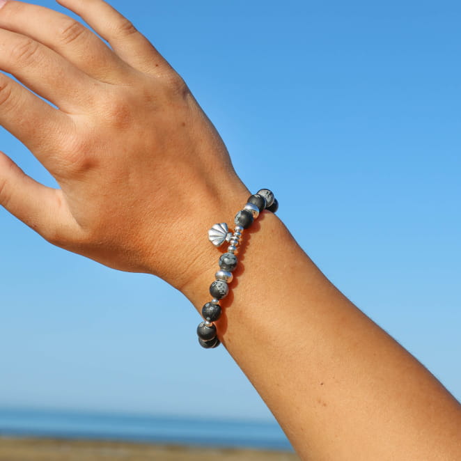 bracelet Konko argenté avec perles noires porté au poignet sur fond bleu ciel