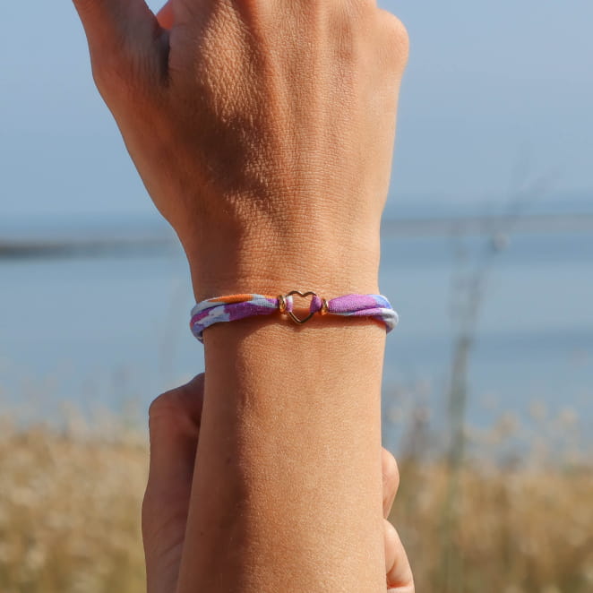 bracelet Maman doré orné d’un cordon violet porté au poignet