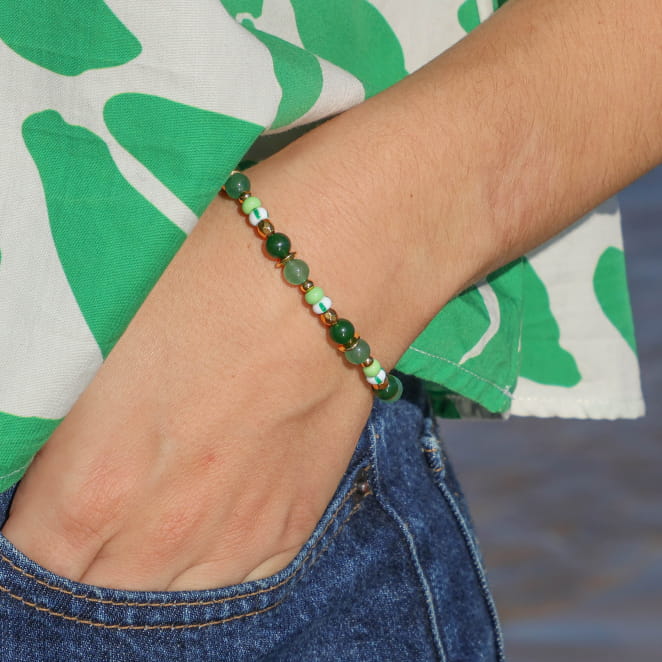 bracelet Martina doré et perles vertes porté sur fond de tissu à motifs