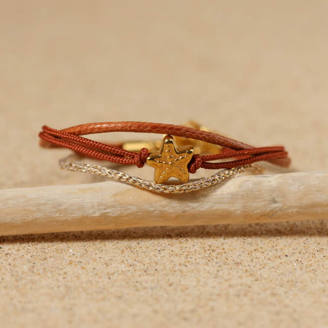 Bracelet doré et marron posé sur sable, fait main en France avec soin