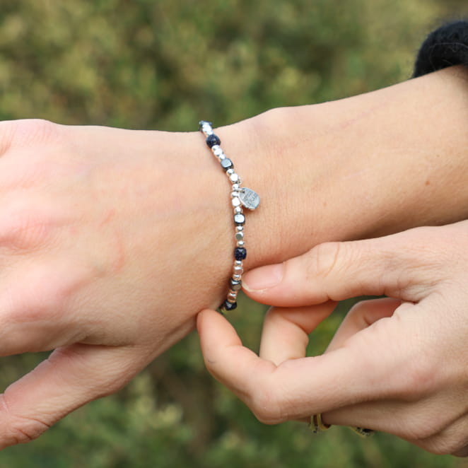 Bracelet argenté orné de perles bleu marine, porté au poignet avec des reflets marins.