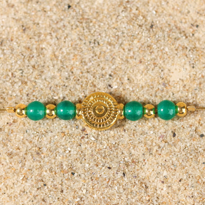 Gros plan du bracelet Tavira sur fond sable – alliance doré et vert profond