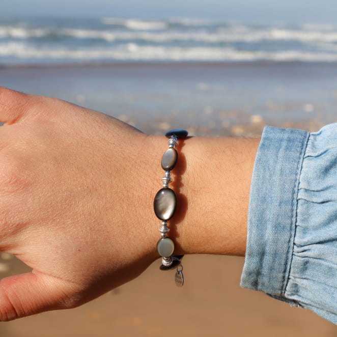 Bracelet argenté à perles facettées gris foncé, porté sur un poignet naturel.